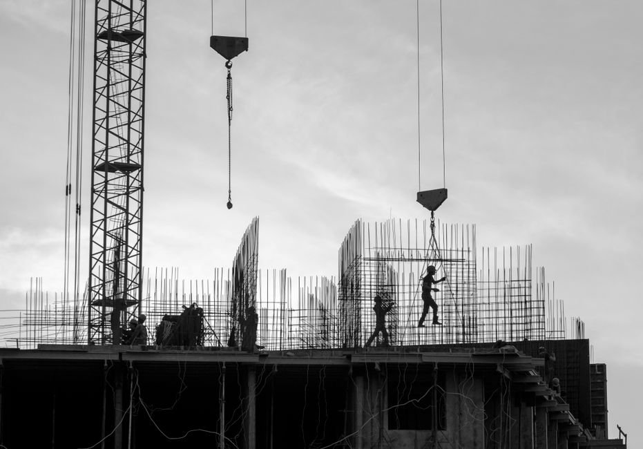 construction site with cranes and workers at sunset