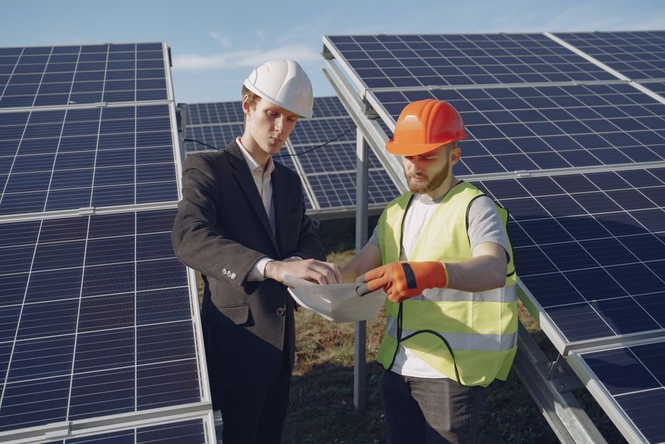 engineers inspecting solar panels and construction blueprints outdoors