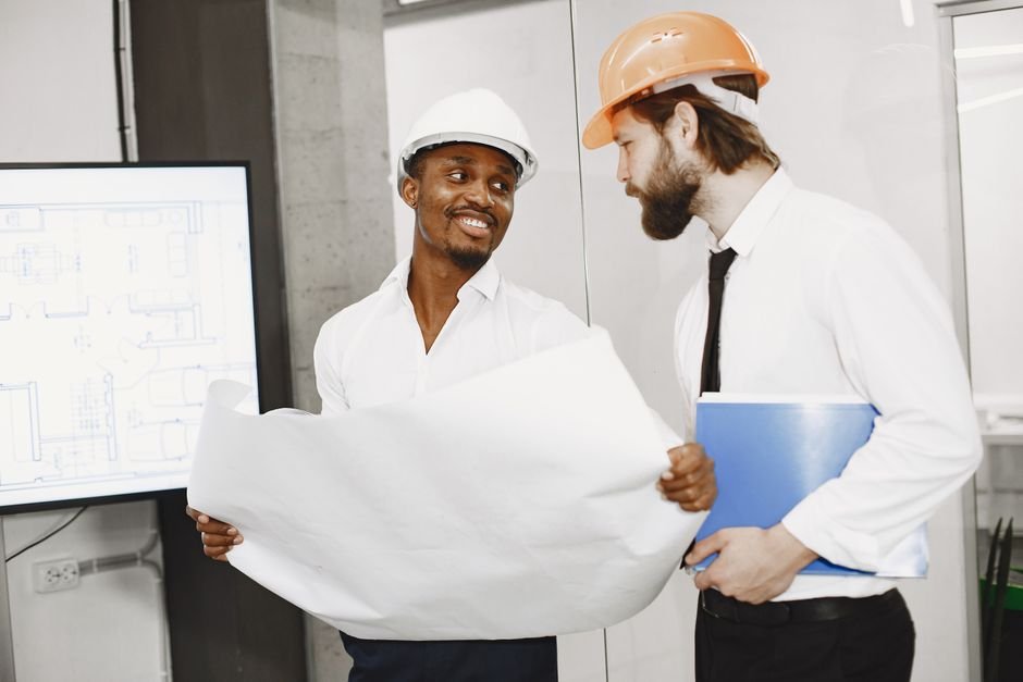 Engineers reviewing construction blueprints and solar battery storage system in a modern industrial plant