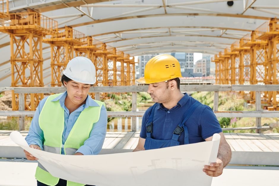 civil engineer reviewing blueprints near water treatment plant construction site