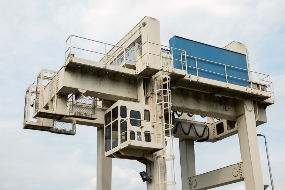 crane lifting large precast concrete beam at construction site