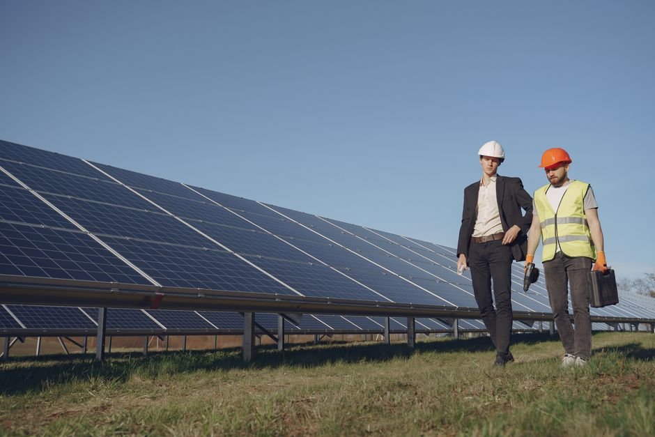 engineers discussing blueprints near solar panels and green energy installation