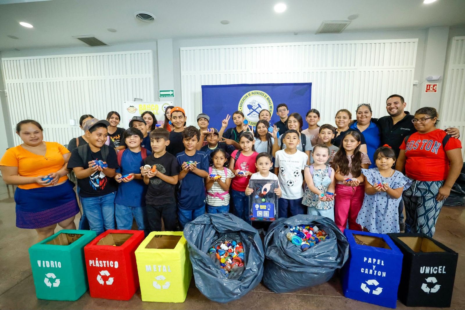 Foto de grupo de las niñas y los niños de La Colorada con las bolsas de tapitas recolectadas y los contenedores de separación de residuos