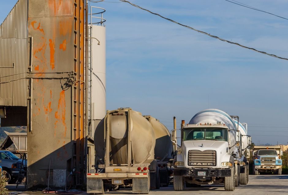 Heavy construction trucks loading cement at a distribution hub