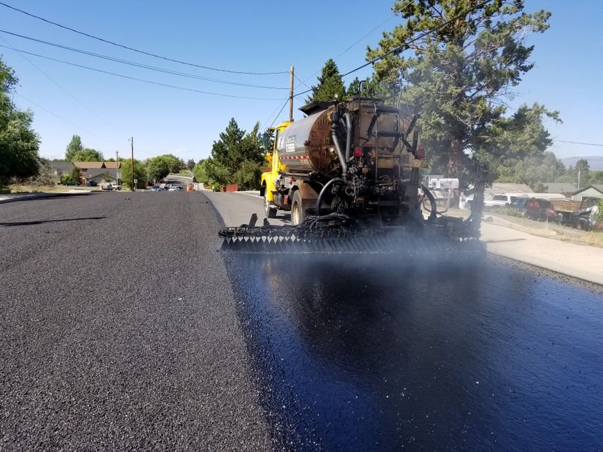 heavy machinery paving a hot desert road under bright sun