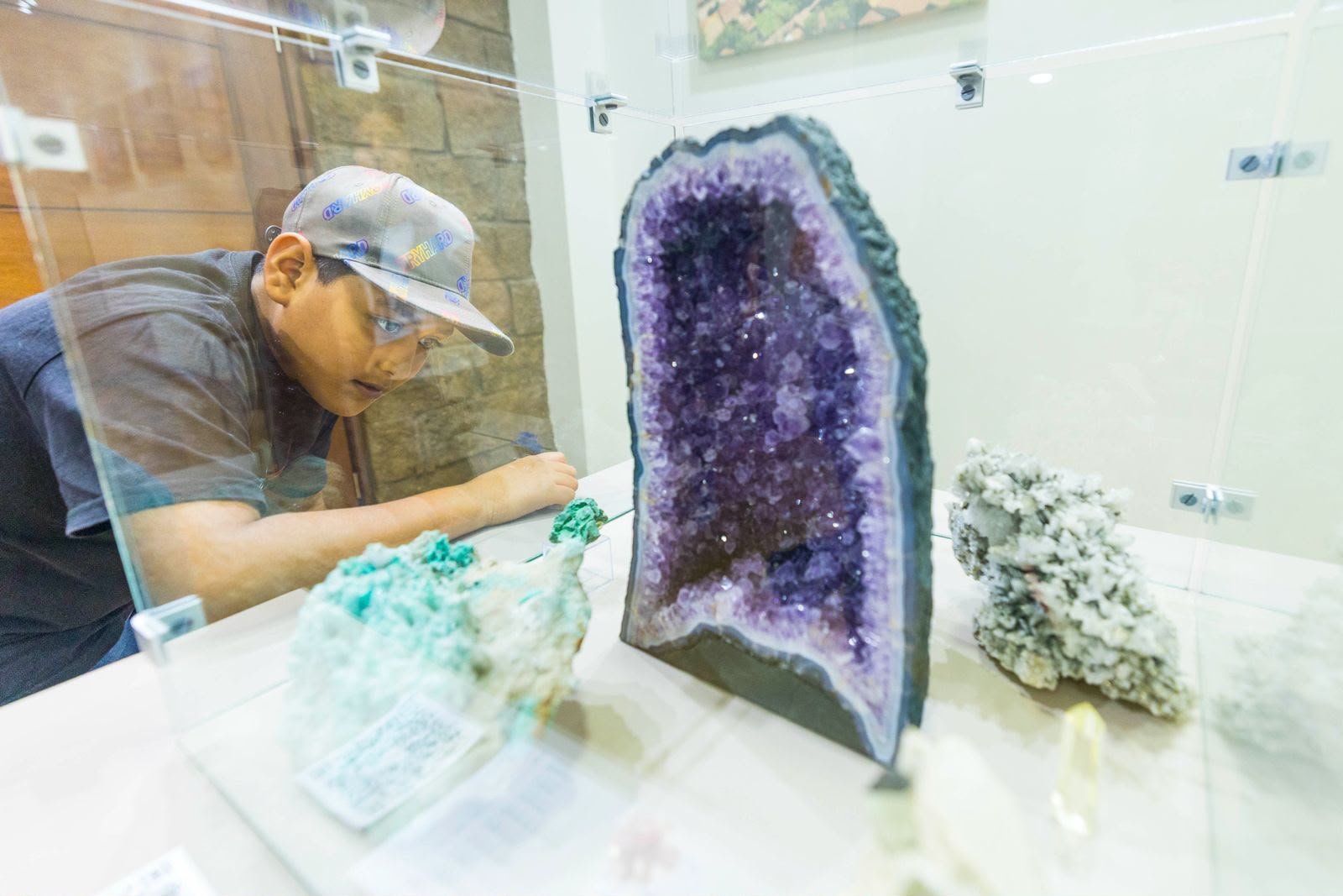 Un niño observa de cerca una geoda de amatista en una vitrina del Museo de Minerales