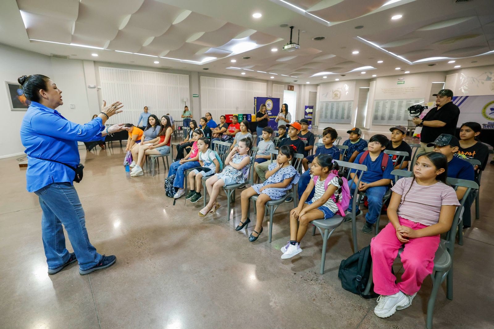 Niñas y niños del campamento de verano de La Colorada escuchan una plática en el auditorio de la AIMMGM Distrito Sonora