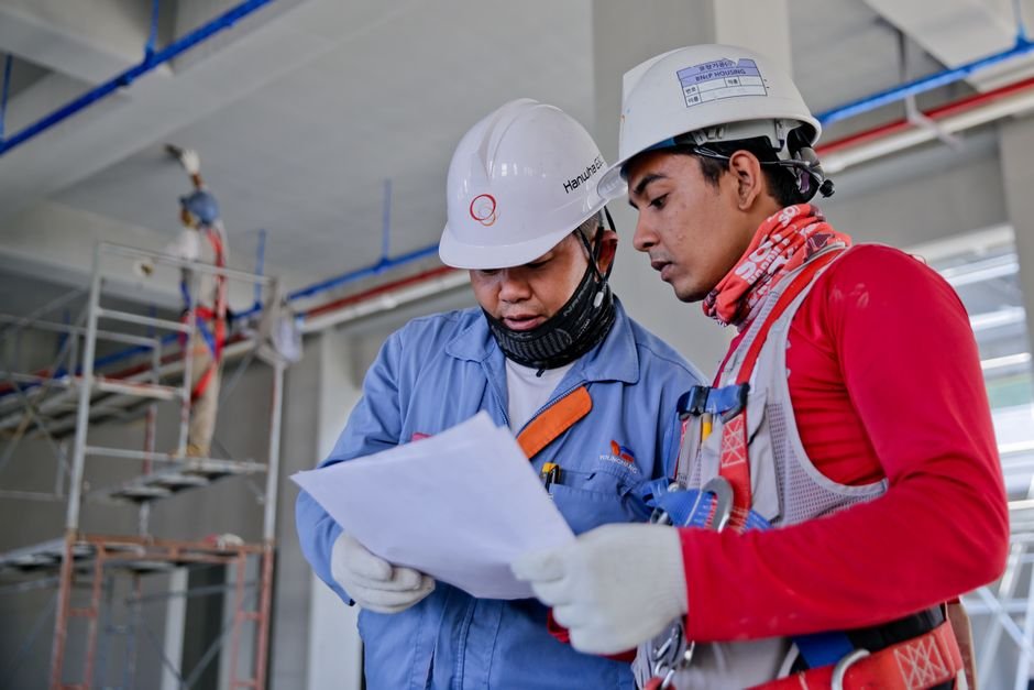 Professional engineers reviewing blueprint plans on a construction site with steel beams