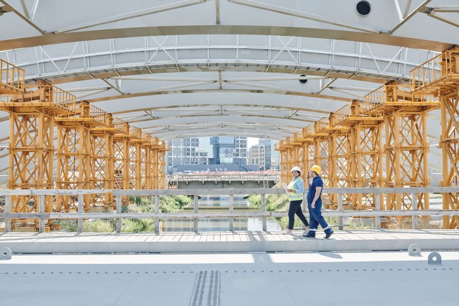 structural engineer inspecting a concrete bridge with tablet in urban environment