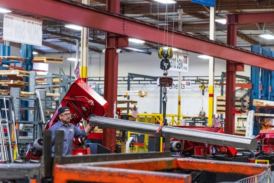 Workers assembling steel structures in a large industrial warehouse
