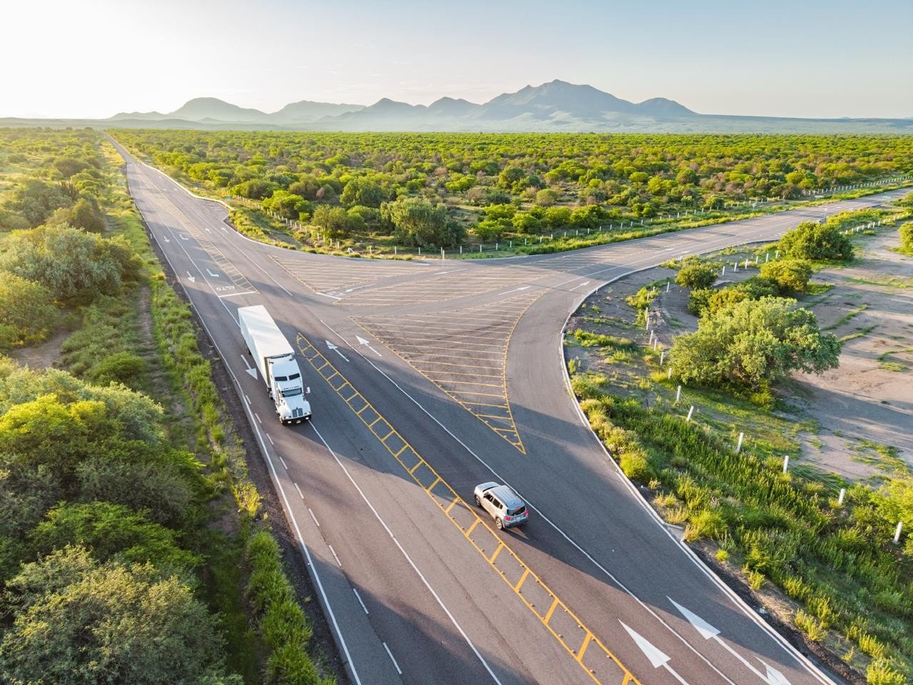 Vista aérea de un entronque carretero en Sonora con un tráiler y una camioneta circulando
