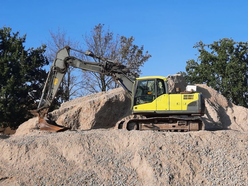 construction engineer analyzing telemetria data on tablet near excavator