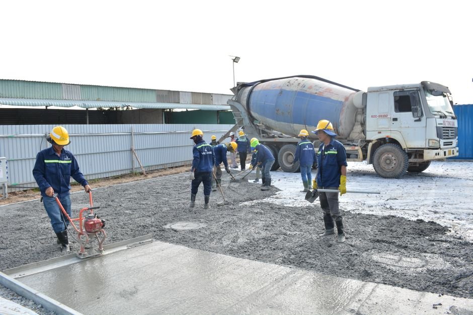 construction workers pouring permeable ecological concrete on a sunny road