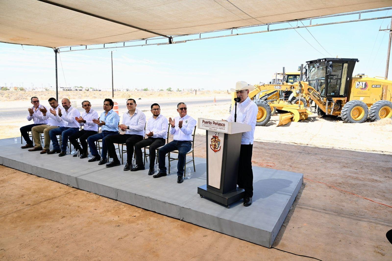 El gobernador Alfonso Durazo Montaño habla en el pódium ante el presídium, con maquinaria de construcción al fondo