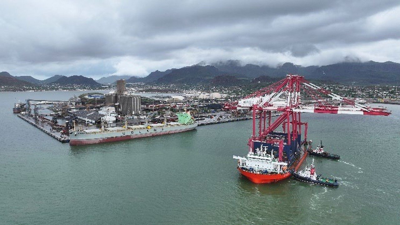 Buque con grúas de pórtico rojas entrando al Puerto de Guaymas asistido por remolcadores