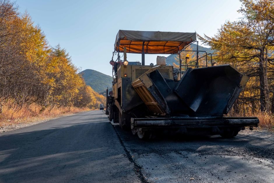 heavy machinery paving modern asphalt road with rubber mixture in sunny desert environment