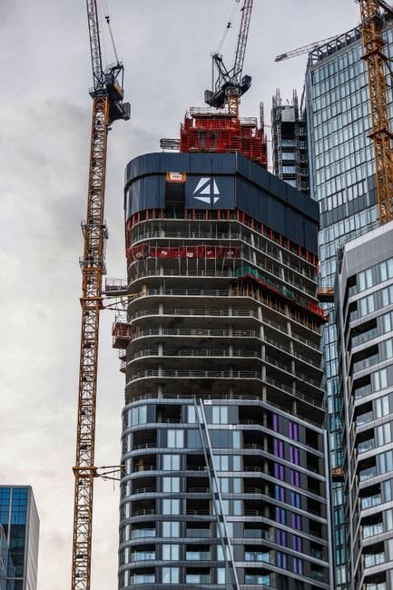 modern commercial building construction site under clear sky with cranes and steel structure