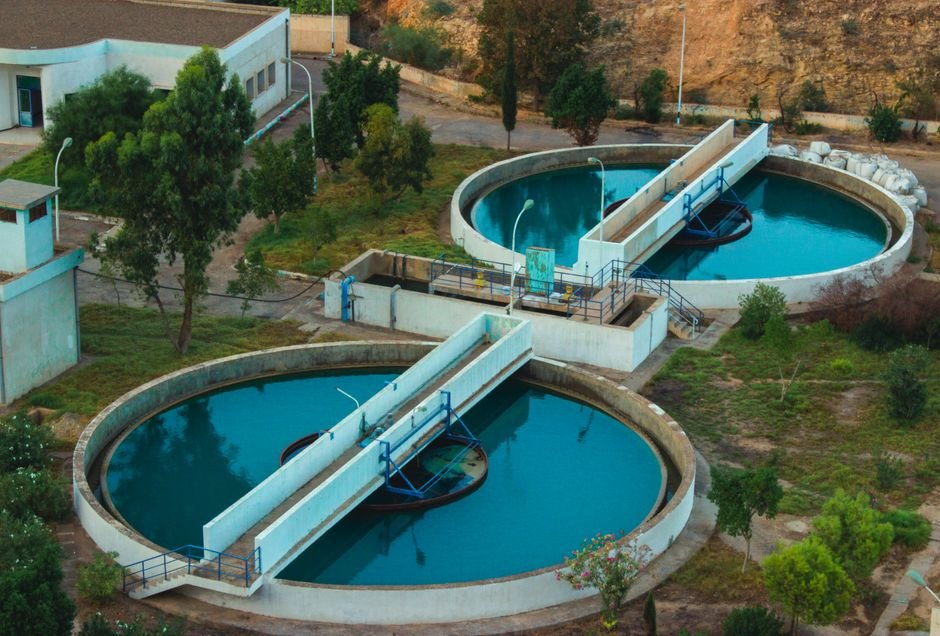 modern wastewater treatment plant construction site with engineers inspecting concrete tanks