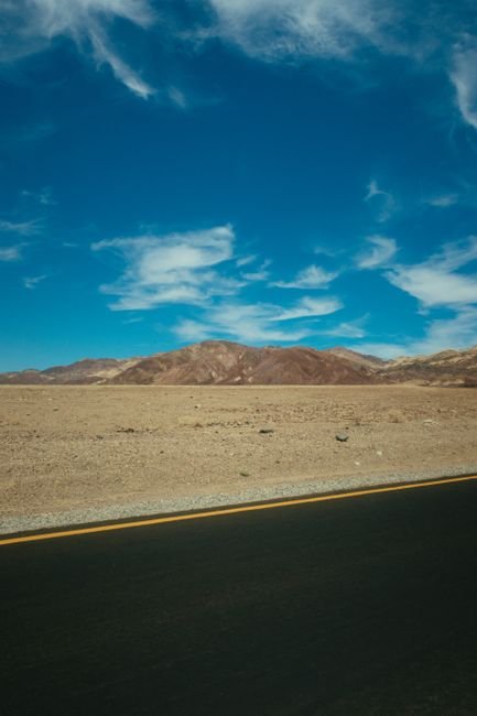 Workers applying hot mix asphalt on a highway in a sunny desert landscape
