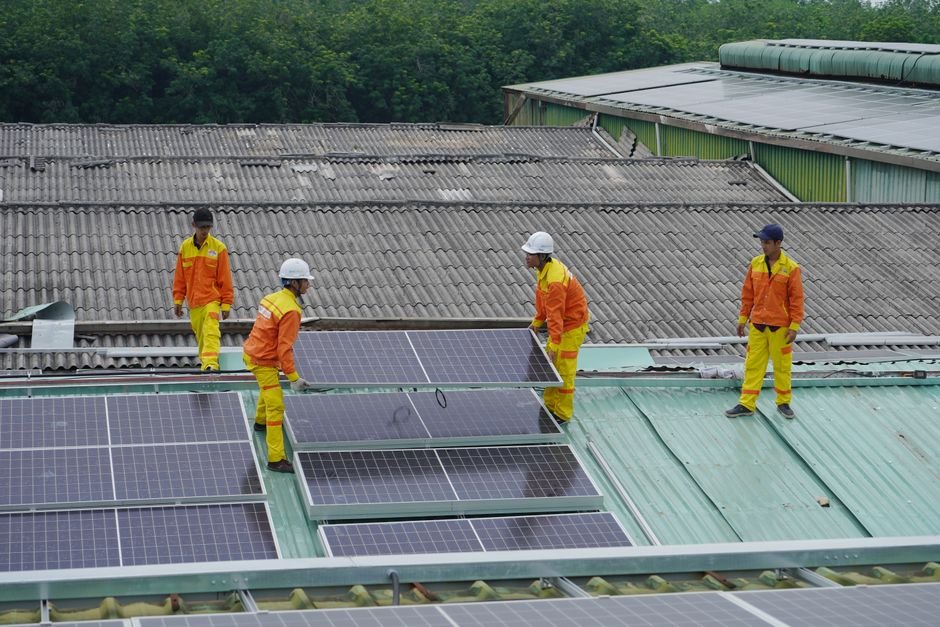 Workers installing solar panels on a large industrial roof in sunny Mexico