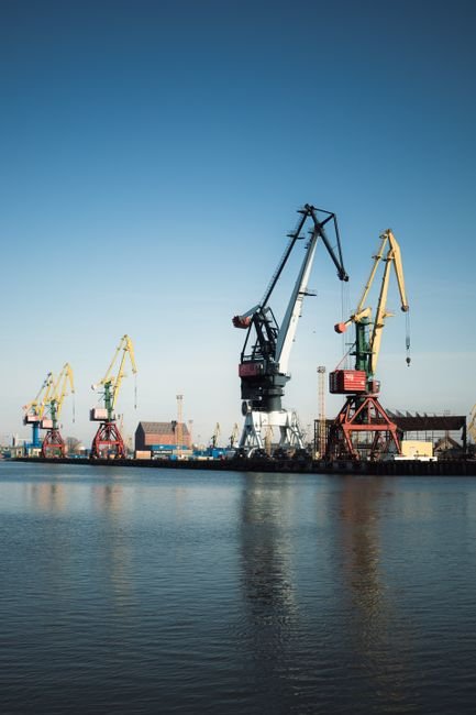 Heavy construction machinery working on a modern seaport dock with industrial cranes