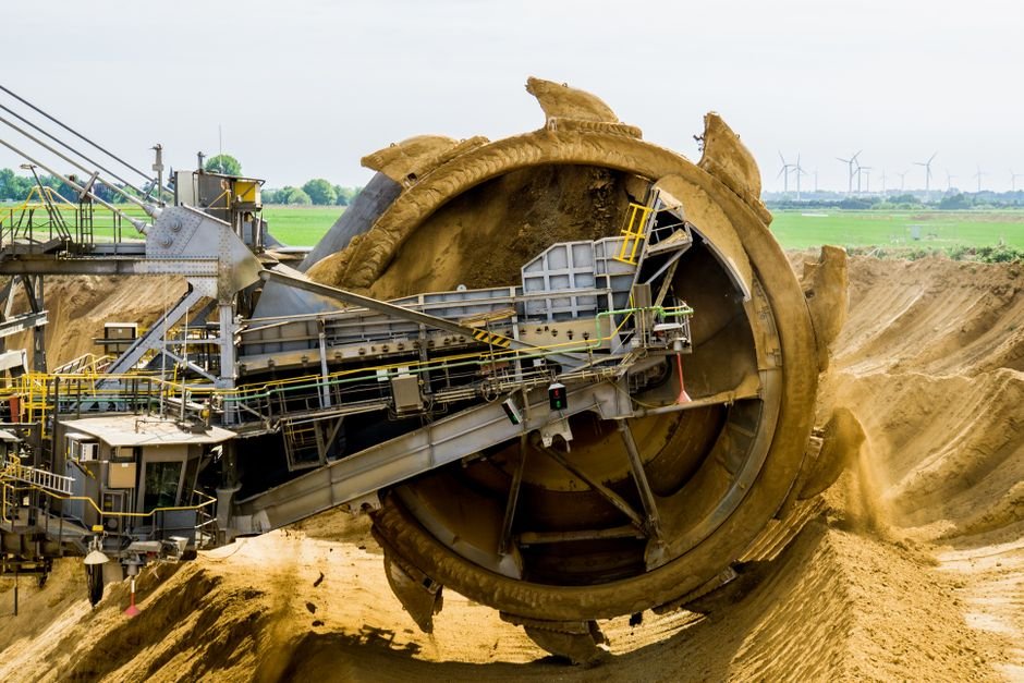 Heavy machinery working in a massive open pit lithium mine in an arid landscape