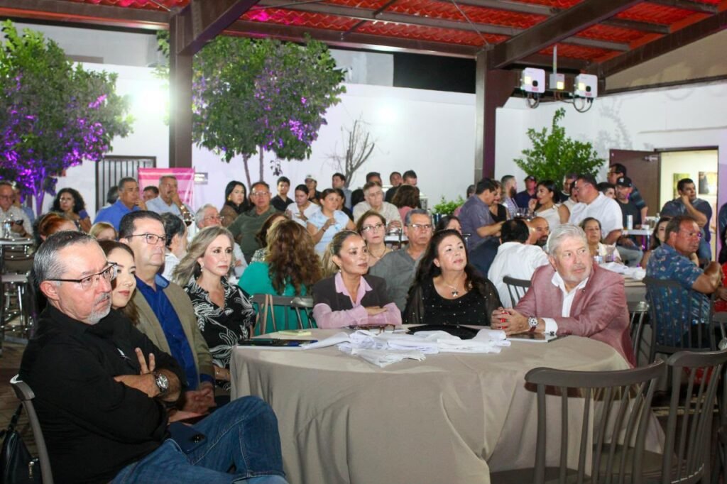 Asistentes sentados alrededor de una mesa escuchan la presentación.