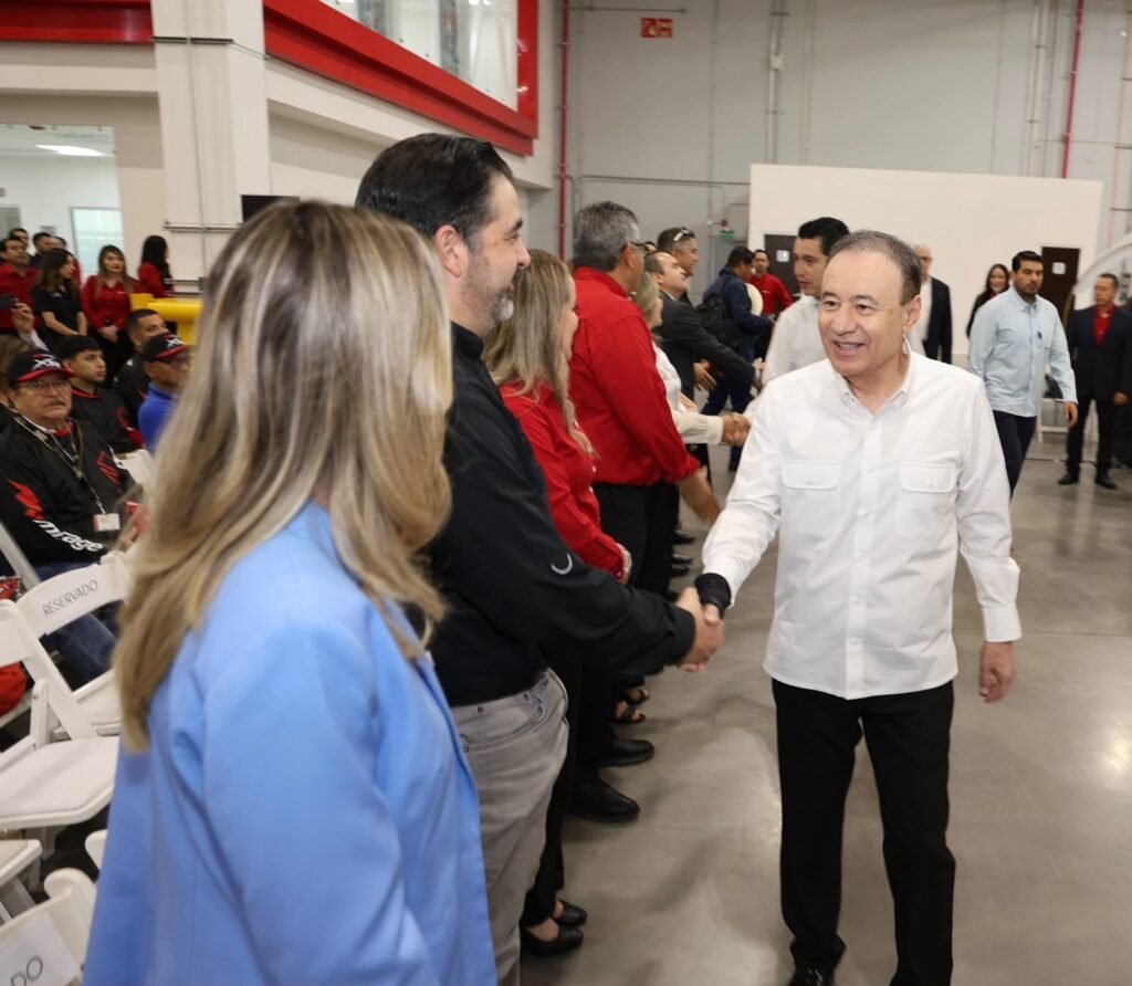 Saludo a trabajadores durante un evento en una nave industrial.