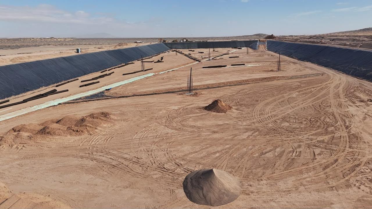 Vista aérea del interior de una celda del relleno sanitario, con taludes cubiertos de geomembrana negra y tubería sobre el fondo de arena.