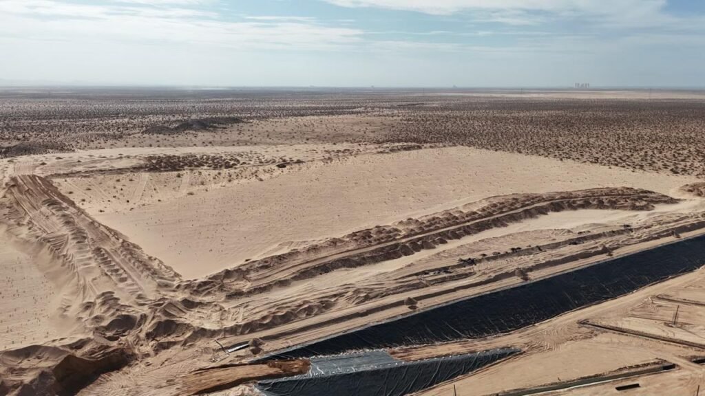 Vista aérea del terreno desértico donde se construye el relleno sanitario; en primer plano, el borde de la celda cubierto con geomembrana.